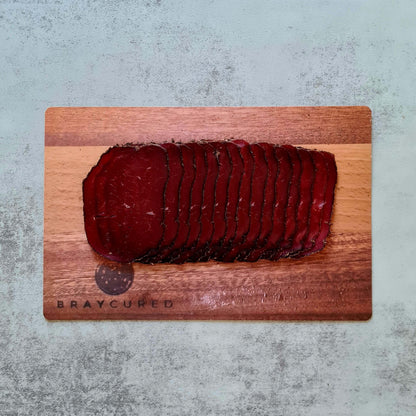 Thin slices of cacao-spiced venison bresaola from Bray Cured served on a charcuterie board with accompaniments.