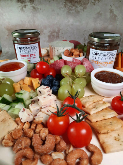 A cheeseboard with assorted cheeses, chutney, and crackers, featuring condiments from The Condiments Kitchen for cheese pairing.