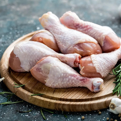 Fresh free-range chicken drumsticks from Primrose Herd, arranged on a white plate ready for cooking.