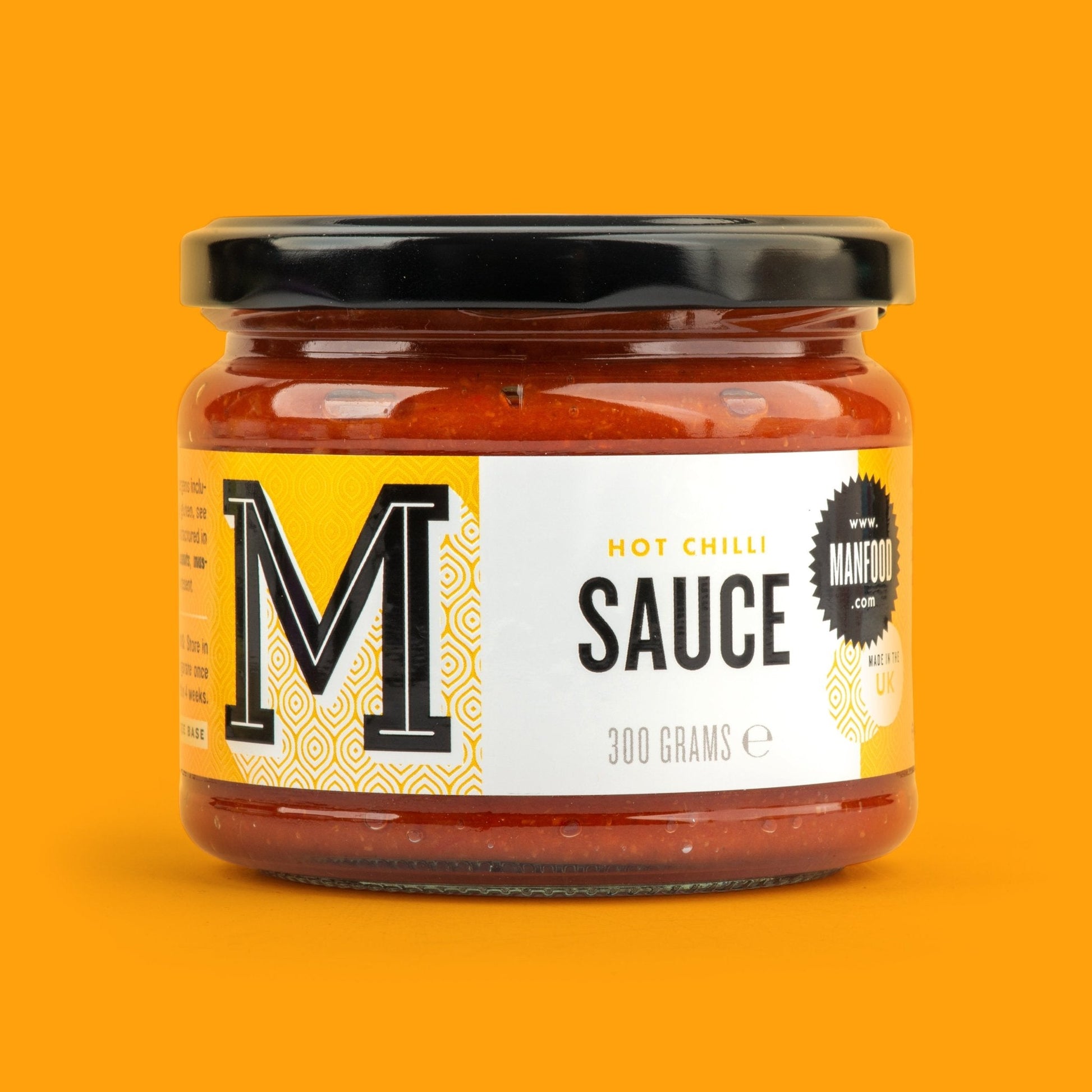 Manfood chili sauce in a glass bottle, vibrant red color, showcasing fresh chili peppers and a spicy, flavorful sauce inside.