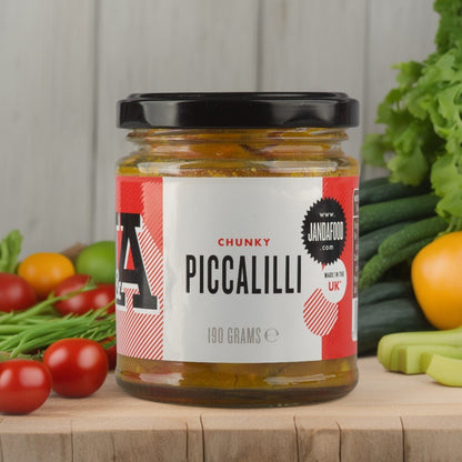 Jar of Janda chunky piccalilli with visible chunks of vegetables and mustard seeds in a clear glass jar.