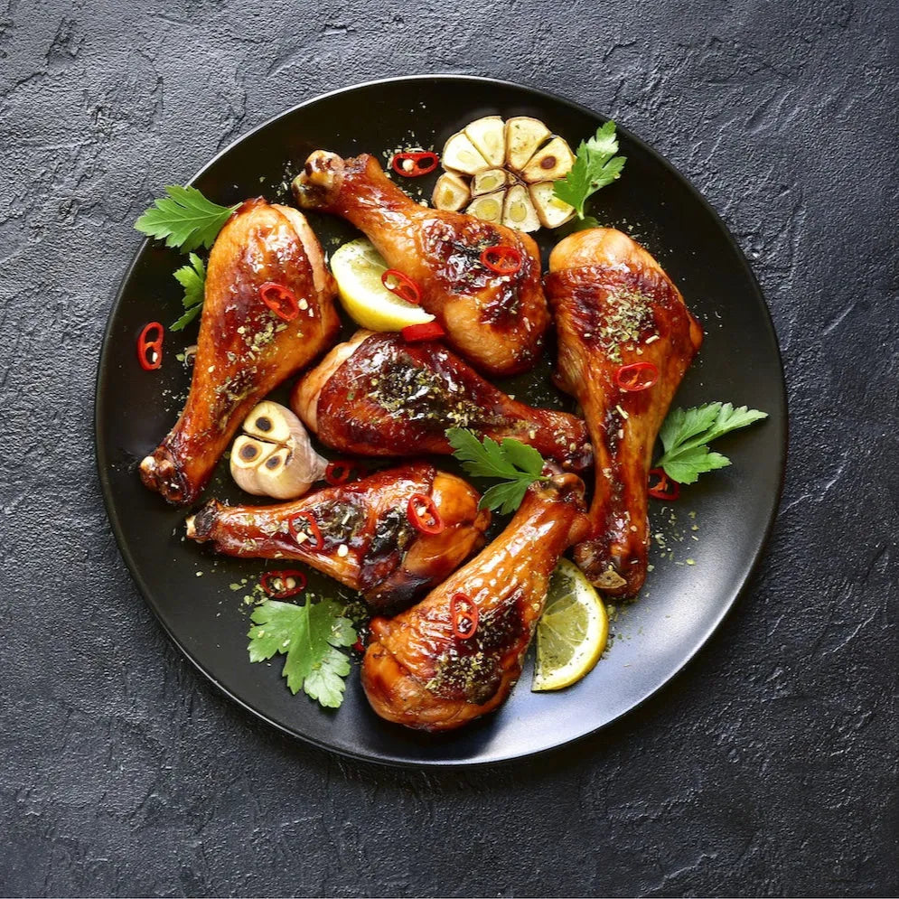 Cooked free-range chicken drumsticks from Primrose Herd, showcasing juicy, tender poultry on a white plate.