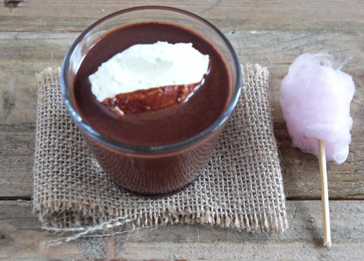 Cup of Gorvett & Stone orange drinking chocolate topped with colorful candy floss, showcasing a rich, creamy beverage with decorative flair.