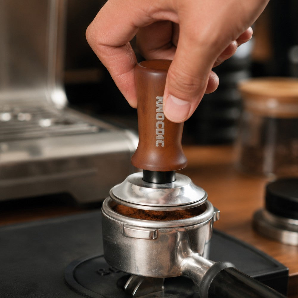 KNOCDIC® espresso tamper with spring-loaded base being used to evenly tamp coffee grounds in an espresso machine portafilter.