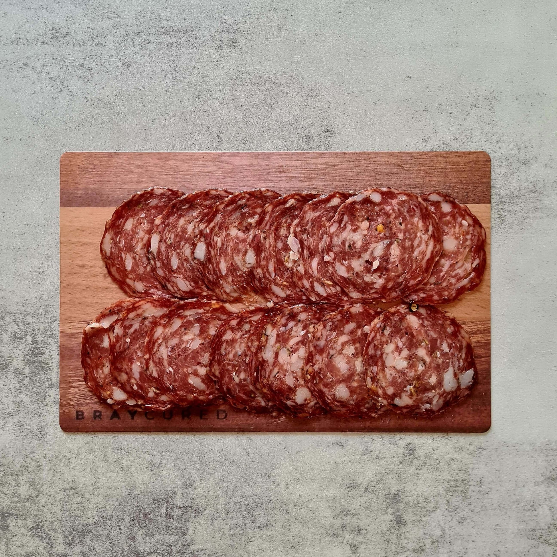 Sliced Bray Cured fennel salami on a charcuterie board with cheese and crackers, showcasing the flavorful cured meat.