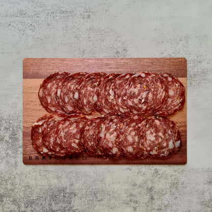Sliced Bray Cured fennel salami on a charcuterie board with cheese and crackers, showcasing the flavorful cured meat.