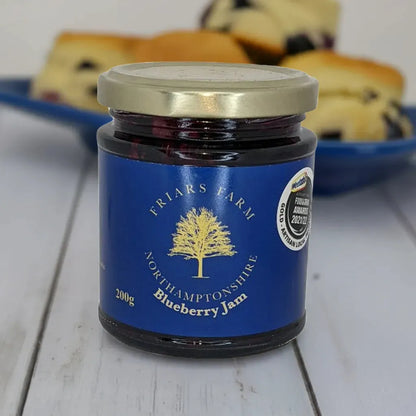 Friars Farm Blueberry Jam 200g jar with a spoon, showing fresh blueberries and vibrant purple jam inside.