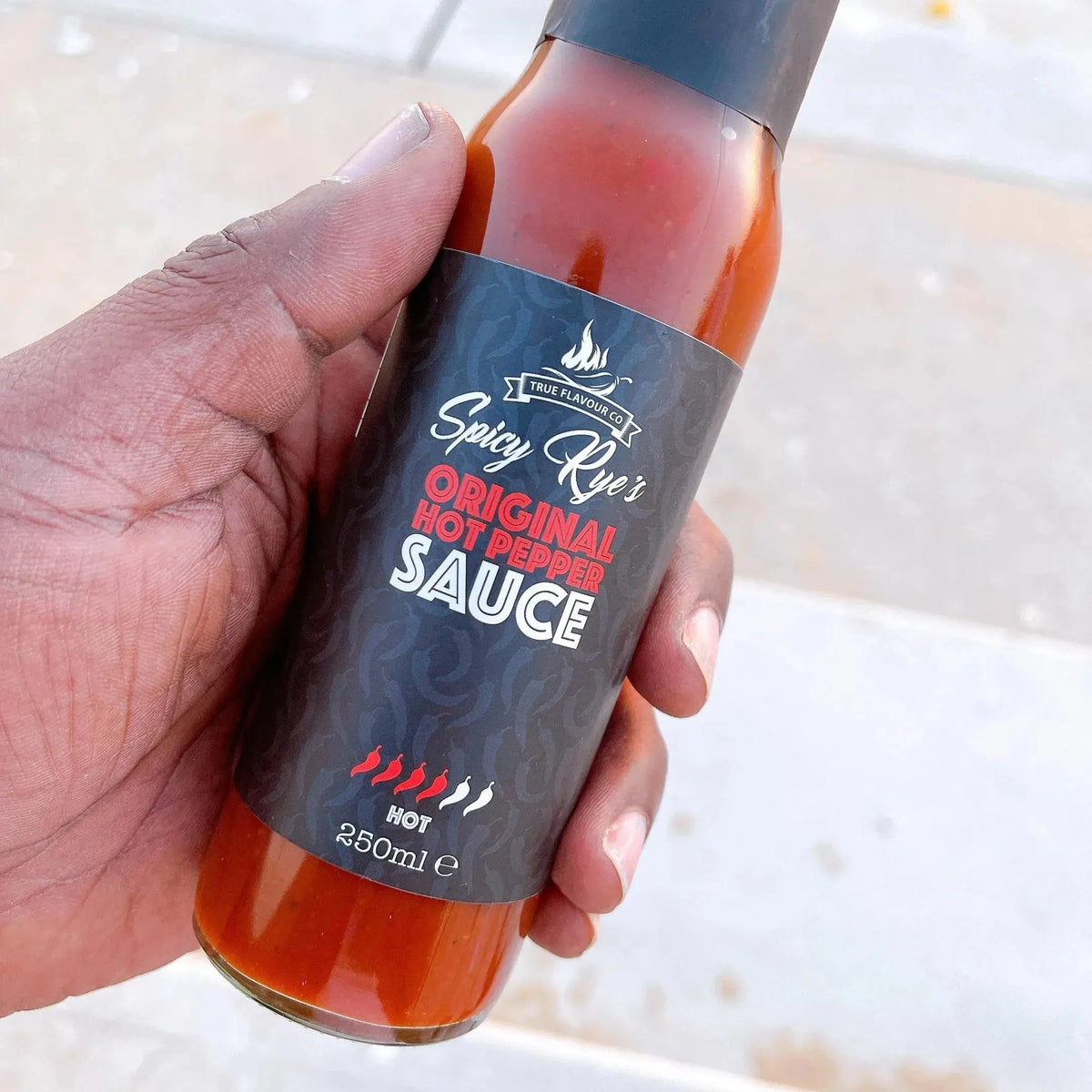 Spicy Ryes Original Hot Pepper Sauce bottle with bright red chili peppers and hot sauce pouring from the bottle.