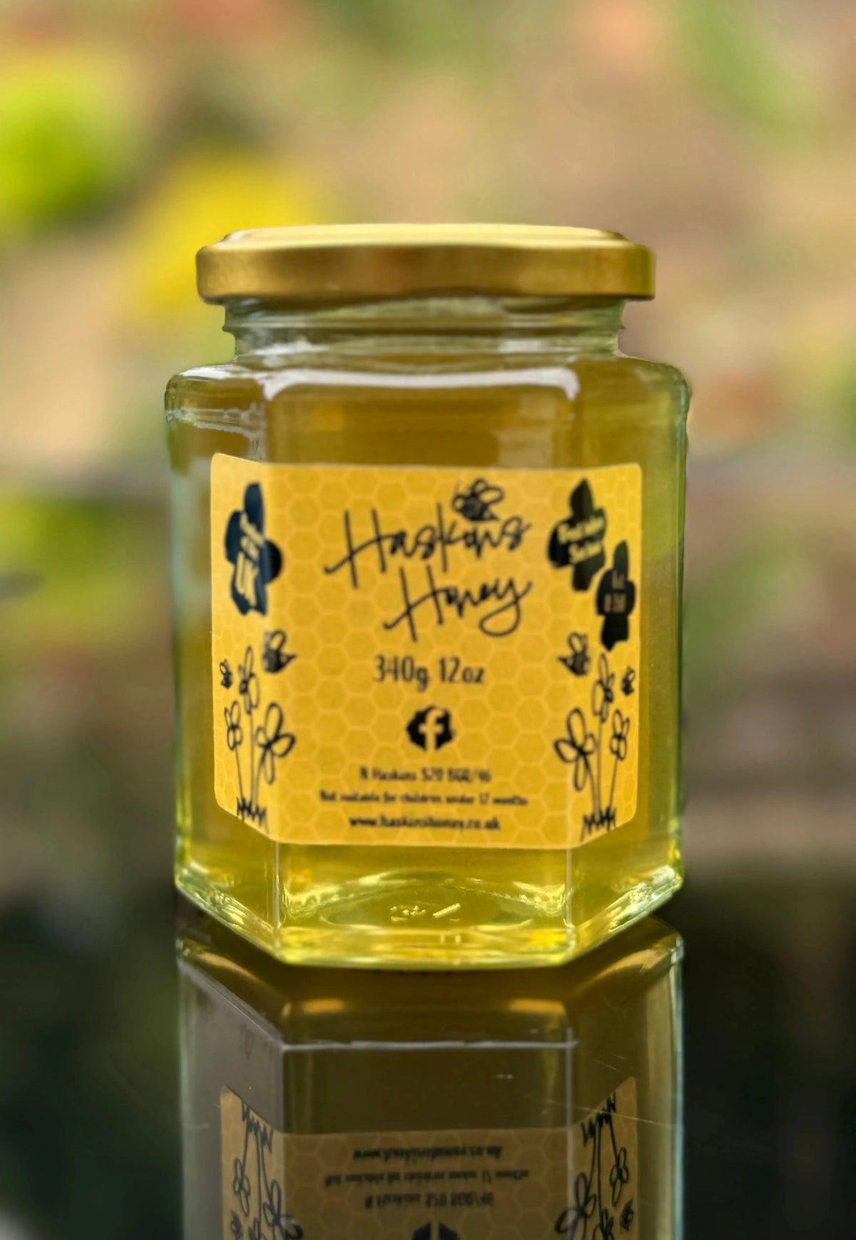 Wildflower Drift honey jar by Haskins Honey with a golden honey dipper and rustic wooden background.
