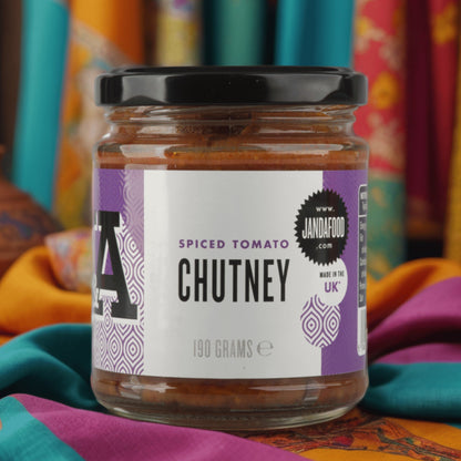 Jar of Janda Spiced Tomato Chutney with rich tomato, spices, and herbs visible on the label and around the jar.