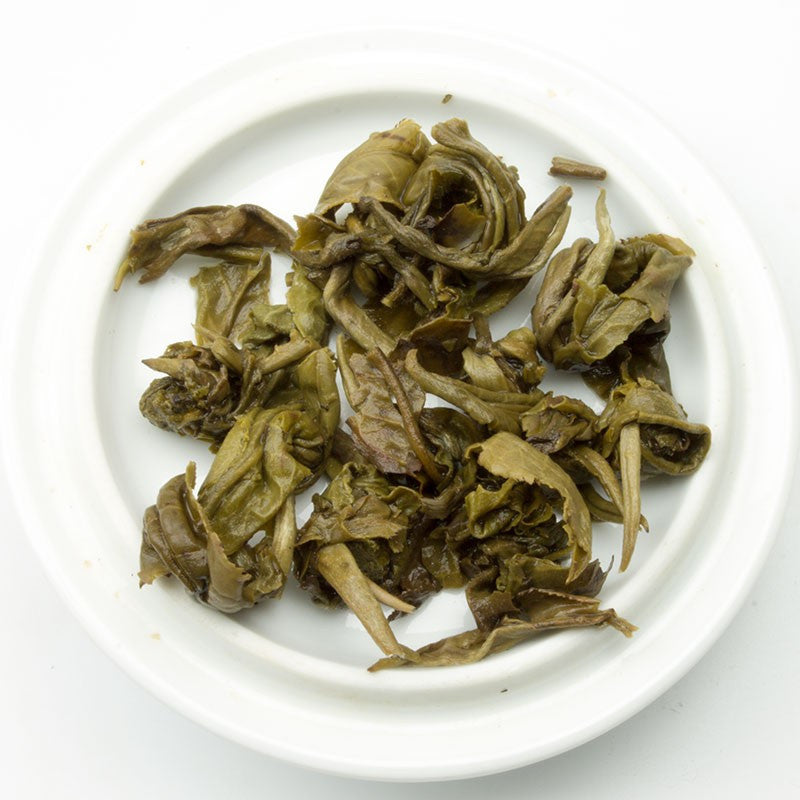 Brewed Jasmine Dragon Pearl Green Tea from PekoeTea Edinburgh in a glass cup, showcasing fragrant green tea pearls.