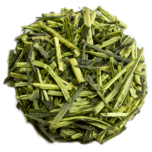 PekoeTea Edinburgh Karigane Kukicha green tea in a teapot with loose tea leaves and a steaming cup on a wooden table.