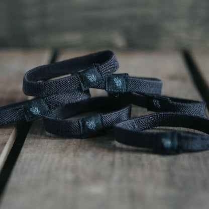 Six black plastic-free hair ties from Wild And Stone, made of eco-friendly materials, shown in a neat pack.