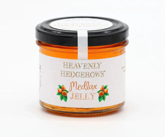 Heavenly Hedgerows Medlar Jelly jar with golden jelly and fresh medlar fruit on a rustic wooden surface.