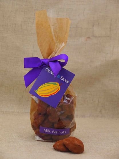 Gorvett & Stone milk walnuts covered in smooth milk chocolate, displayed in a close-up shot showing the chocolate coating.