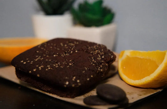 Vegan Chocolate Orange Cake from The Healthy Cake Company, decorated with orange slices and chocolate glaze, on a white plate.