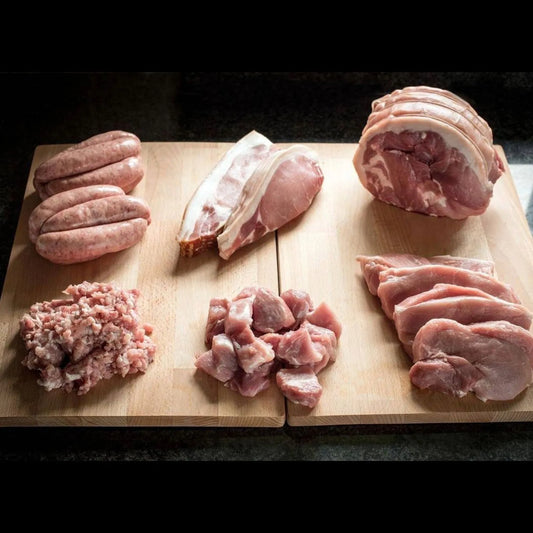 Primrose Herd Pork Taster Box featuring assorted pork cuts in a meat box with packaging and fresh meat visible.