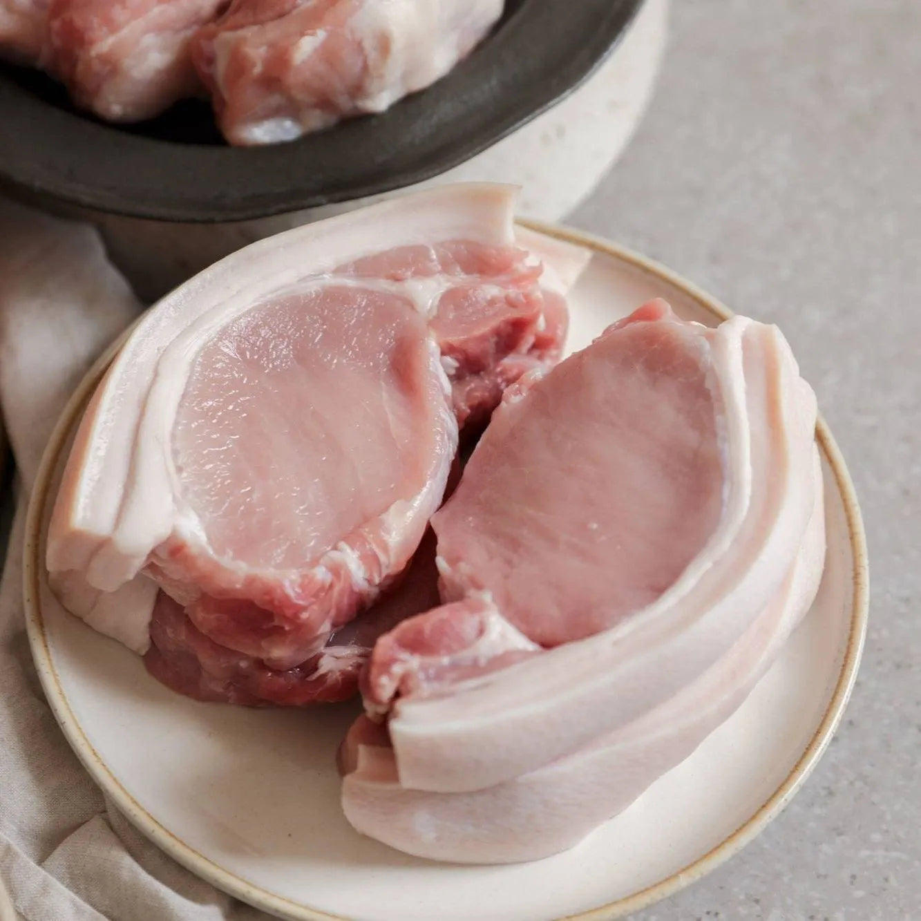Primrose Herd pork loin steaks, fresh and uncooked, showing thick, juicy pork steaks with marbled fat on a white background.