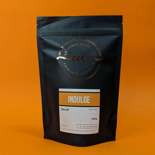 Medium filter roast coffee by Cuckfield Coffee Co. displayed in a bag with coffee beans and brewing equipment in the background.