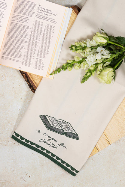 Avalon Home UK Recipe For Disaster Bone China Plate, featuring a detailed design, displayed on a table with a matching teatowel.