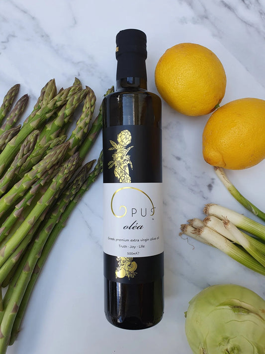 Opus Oléa Extra Virgin Greek Olive Oil in a 500ml glass bottle, showcasing the olive oil with fresh vegetables in the background.