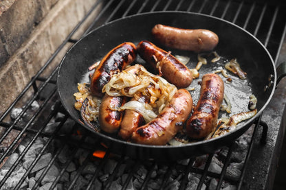 Cornish gluten-free heritage pork cocktail sausages from Primrose Herd sizzling in a pan, ready to serve.