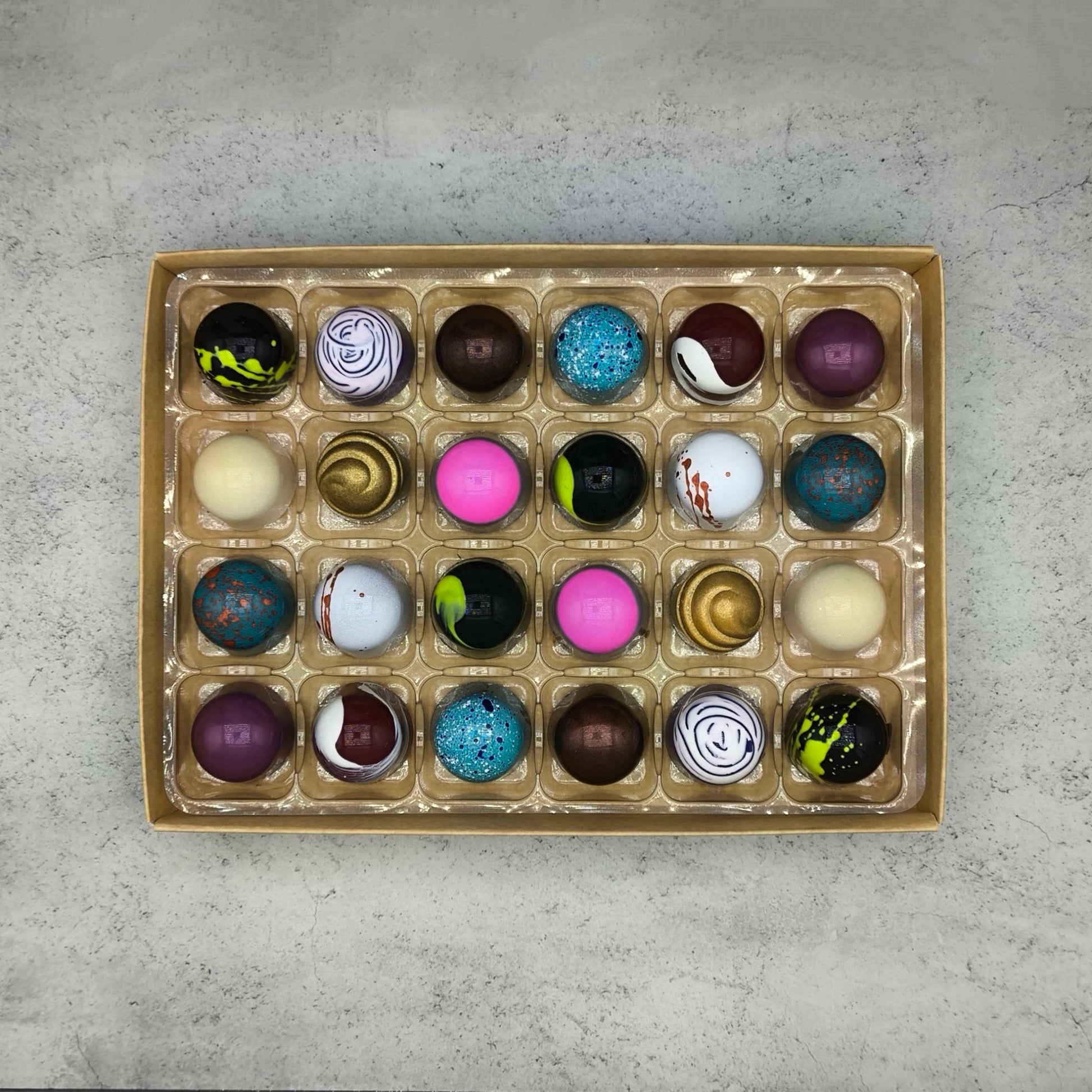 Assorted Trufflus artisan bonbons in a box, showcasing vibrant, handcrafted chocolates with colorful wrappers and elegant presentation.