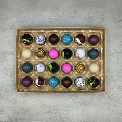Assorted Trufflus artisan bonbons in a box, showcasing vibrant, handcrafted chocolates with colorful wrappers and elegant presentation.