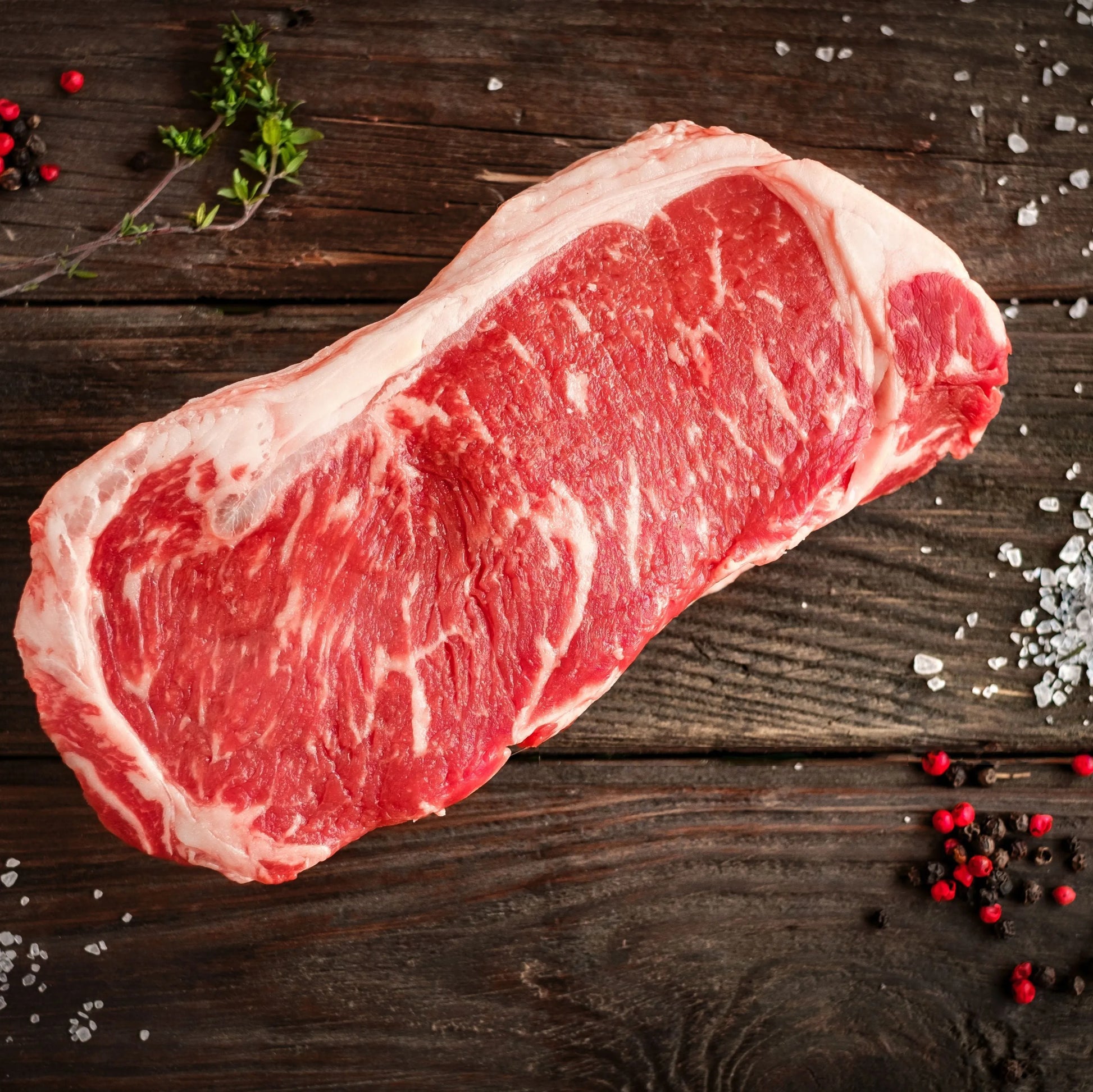 Primrose Herd dry-aged beef sirloin steaks, thick cut with marbled meat and a rich, deep red color on a wooden cutting board.