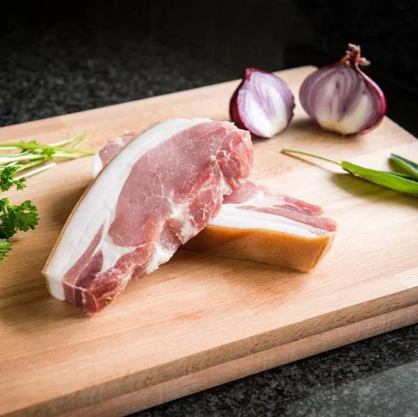 Primrose Herd smoked bacon chop showing a juicy, well-cooked pork chop with smoky glaze and grill marks on a plate.
