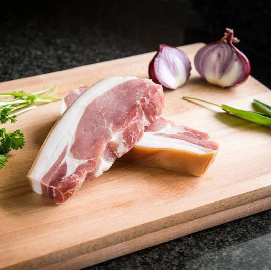 Primrose Herd smoked bacon chop showing a juicy, well-cooked pork chop with smoky glaze and grill marks on a plate.