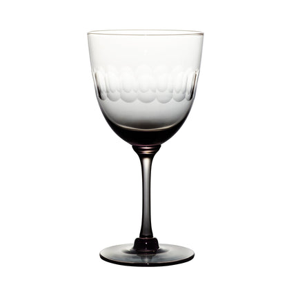 Four smoky crystal wine glasses with lens design from The Vintage List, showing elegant, modern glassware on a neutral background.