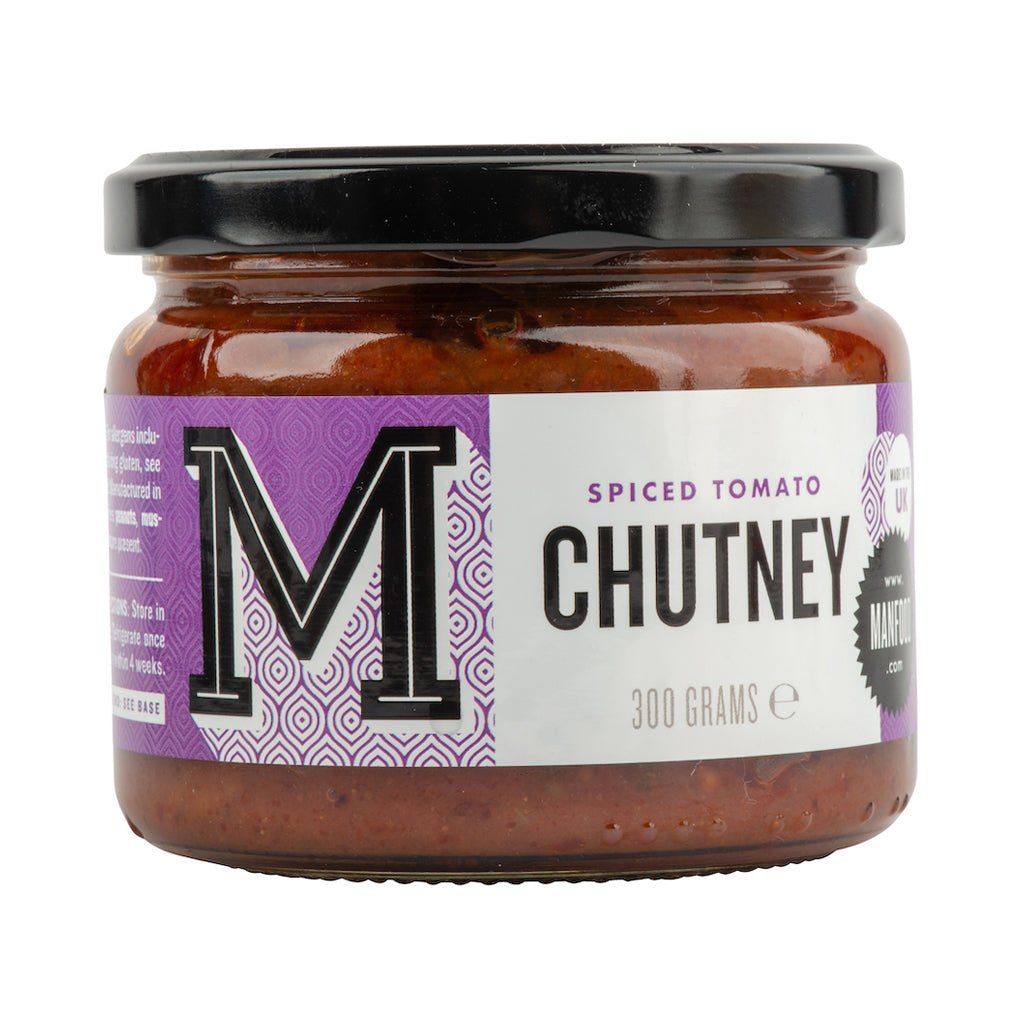 Spiced tomato chutney in a jar by Manfood, showing vibrant red color and textured surface with spices and herbs visible.