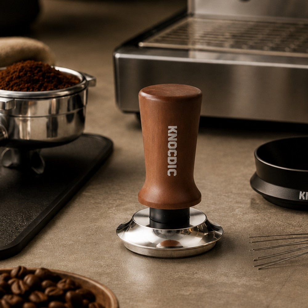 KNOCDIC® espresso tamper with spring-loaded base, showing ergonomic handle and polished metal surface for professional coffee brewing.