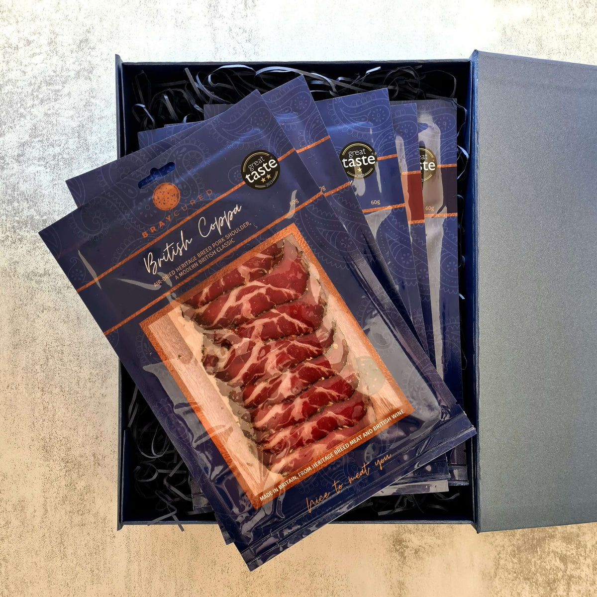 Assorted Bray Cured charcuterie selection with five packs of cured meats in a box, showcasing a variety of slices and textures.