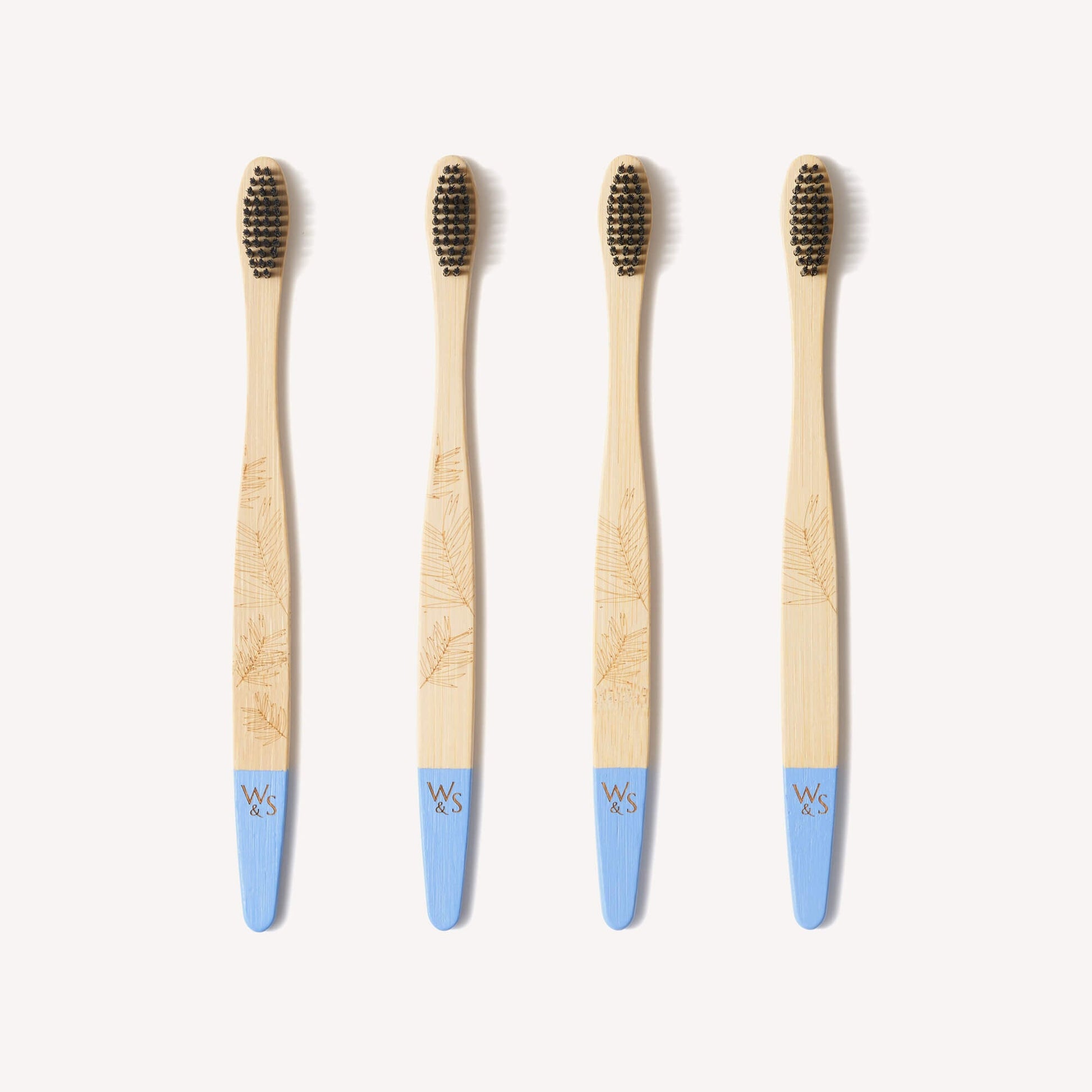 Four adult bamboo toothbrushes with firm bristles from Wild and Stone, featuring natural bamboo handles.