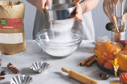 Organic Arrowroot powder from Whole Food Earth, GMO-free and vegan, shown in a clear container on a wooden surface.