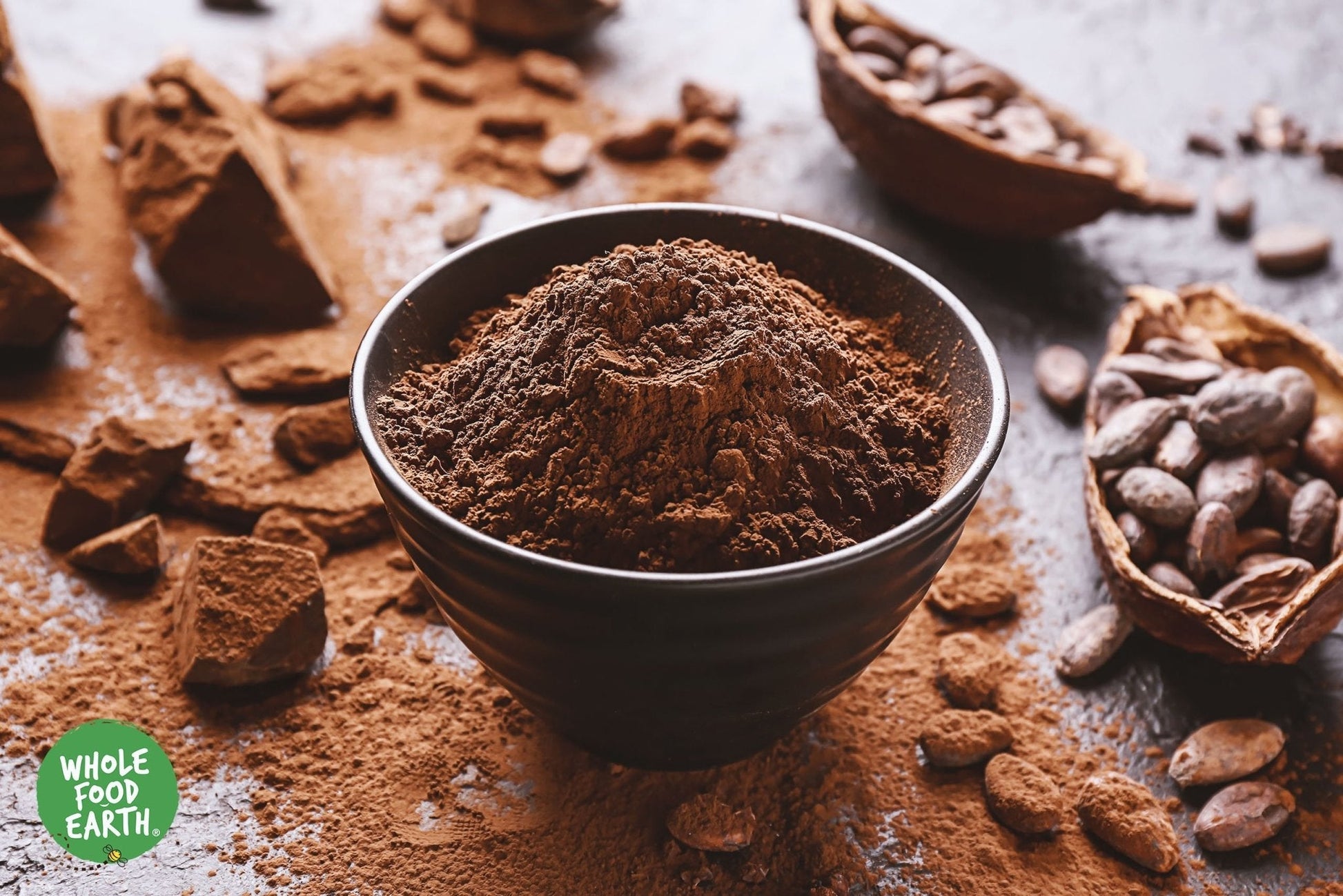 Organic alkalised cocoa powder in a container, showing a natural brown color, labeled as Whole Food Earth specialty vegan cocoa powder.
