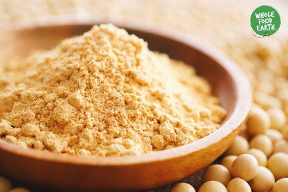 Organic toasted soya flour from Whole Food Earth, GMO-free, displayed in a clear bag on a wooden surface.