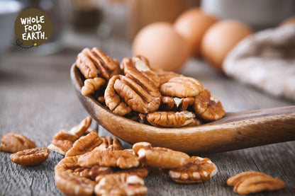 Raw Whole Food Earth pecan halves, GMO-free nuts and seeds, showing light brown, crunchy pecan pieces on a neutral background.